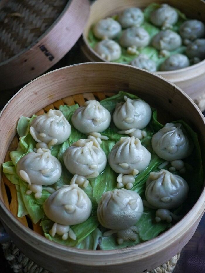 Steamed dumplings shaped like smiling faces on cabbage leaves in a bamboo steamer, creative meals for kids from Japan.