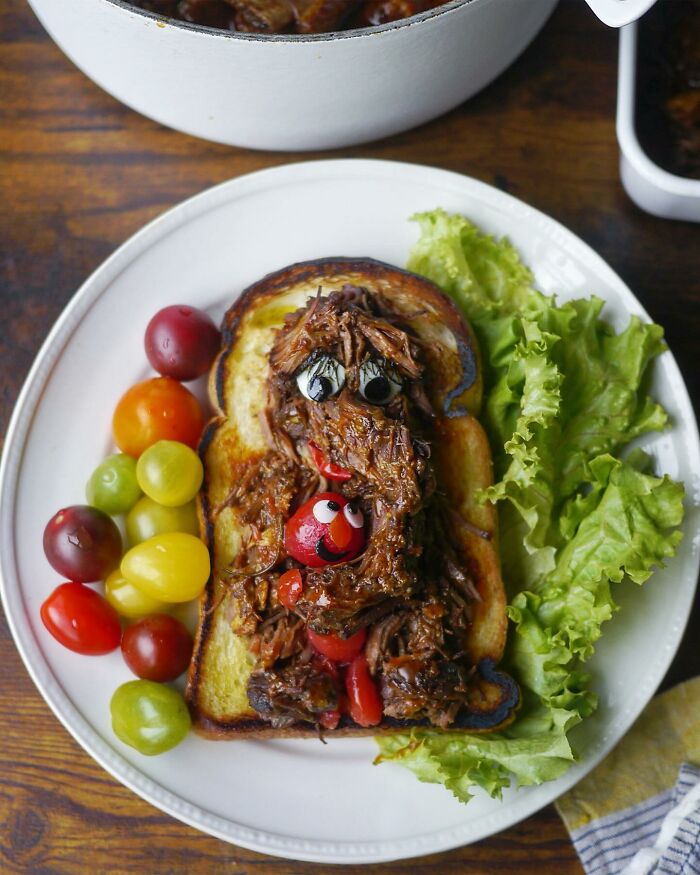 Creative meal by Japanese mom featuring a fun sandwich with shredded meat, cherry tomatoes, and fresh lettuce on a white plate.