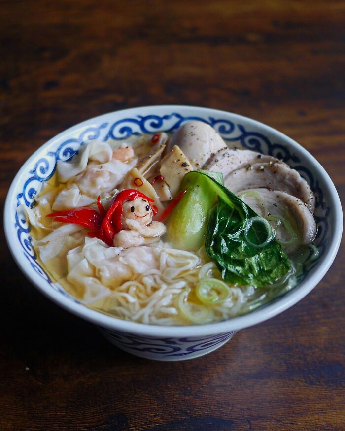 Bowl of creative Japanese kids meal with noodles, chicken, greens, and a cute mermaid-shaped food decoration.
