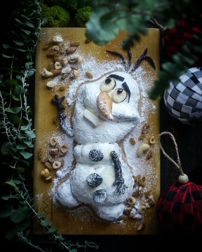 Creative meal shaped like Olaf the snowman dusted with powdered sugar and nuts on a wooden board for kids by a Japanese mom.