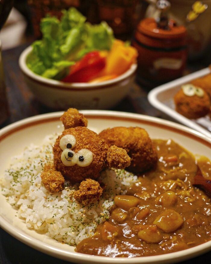 Creative Japanese mom's meal featuring a bear-shaped fried food artfully served with rice and curry for kids.
