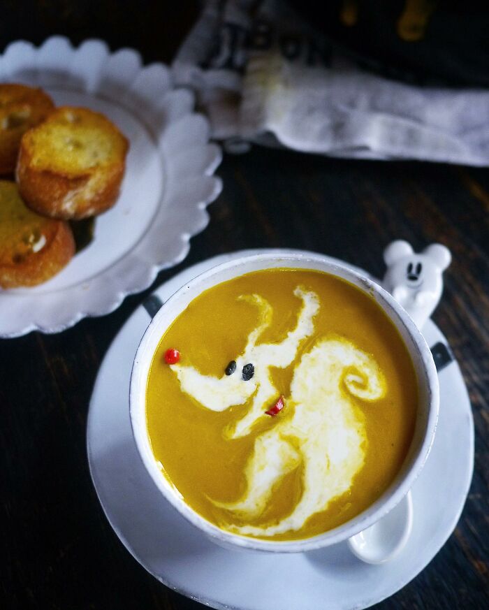 Creative meals for kids featuring pumpkin soup with a dragon design made from cream and vegetables in a white bowl.