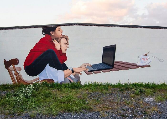 Colorful mural by Artez showing two people with a laptop and a coffee cup, bringing cities to life with vibrant street art.