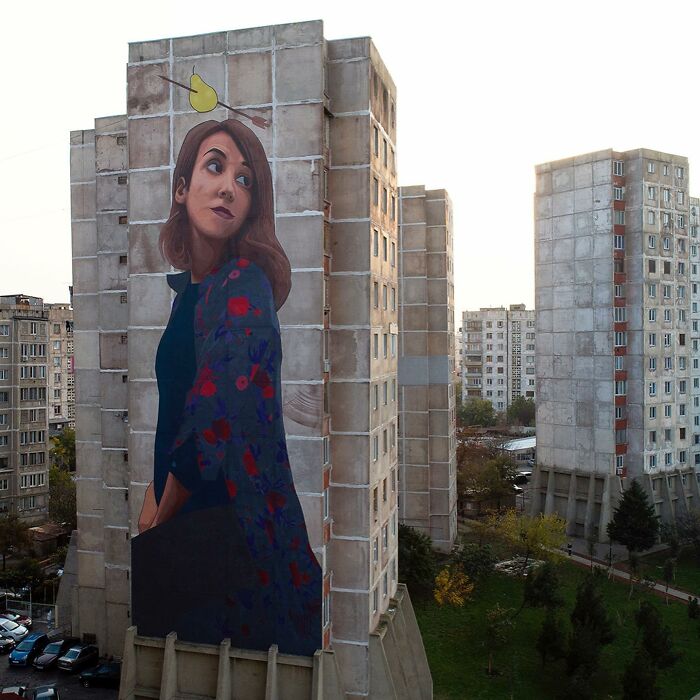 Large colorful mural of a woman on a city building wall, showcasing vibrant street art by Artez in an urban setting.