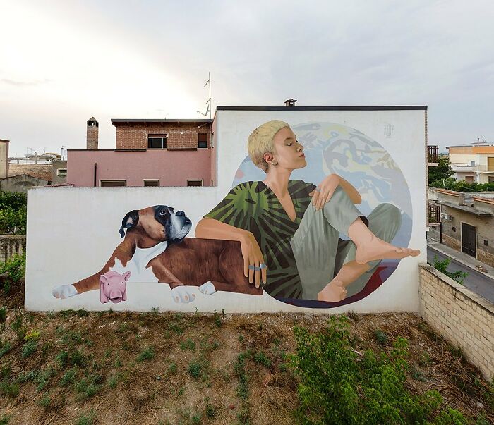 Colorful mural by Artez showing a relaxed woman and dog painted on an urban building wall.