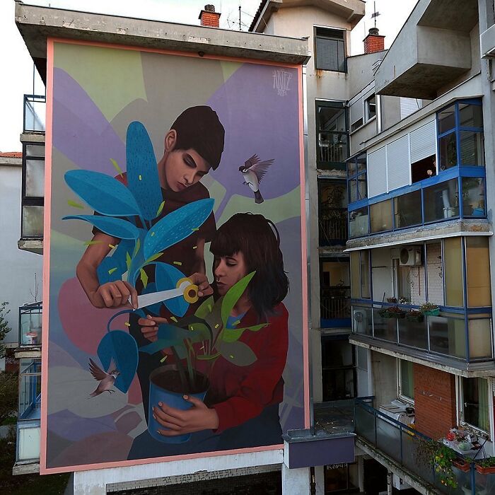 Colorful mural by Artez on building wall depicting two people tending a plant with birds flying nearby, vibrant city street art.