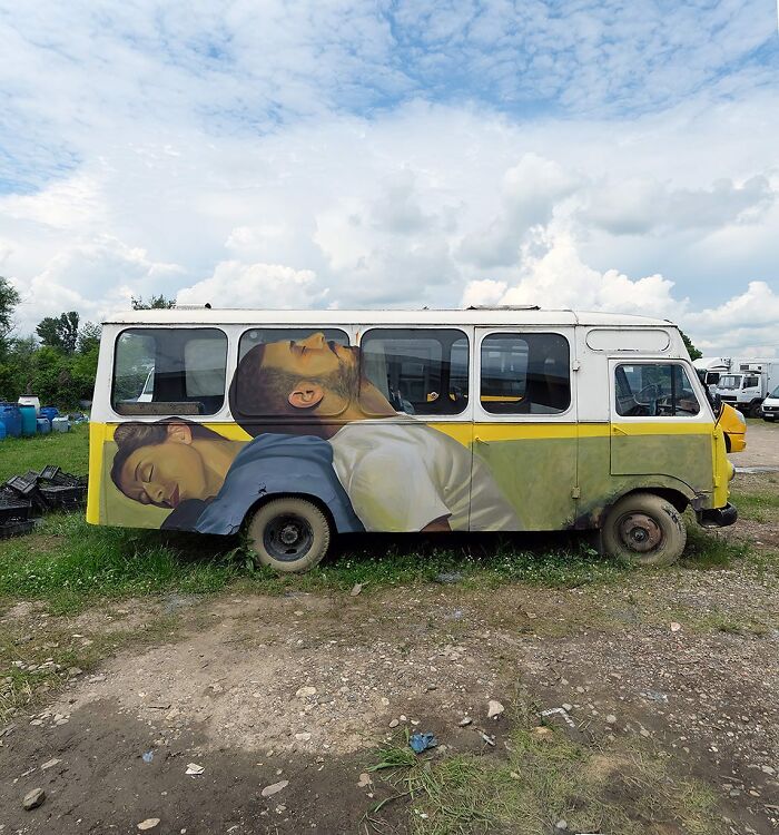 Old van featuring colorful murals by Artez depicting two sleeping people, blending art with urban life.