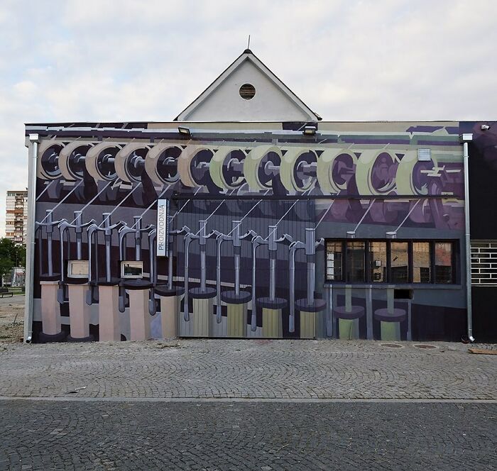 Colorful mural by Artez on a building wall featuring abstract mechanical and industrial elements in urban setting.