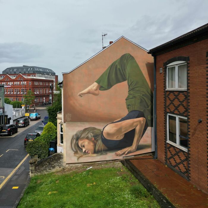 Large colorful mural by Artez of a woman in a yoga pose painted on the side of a city building.