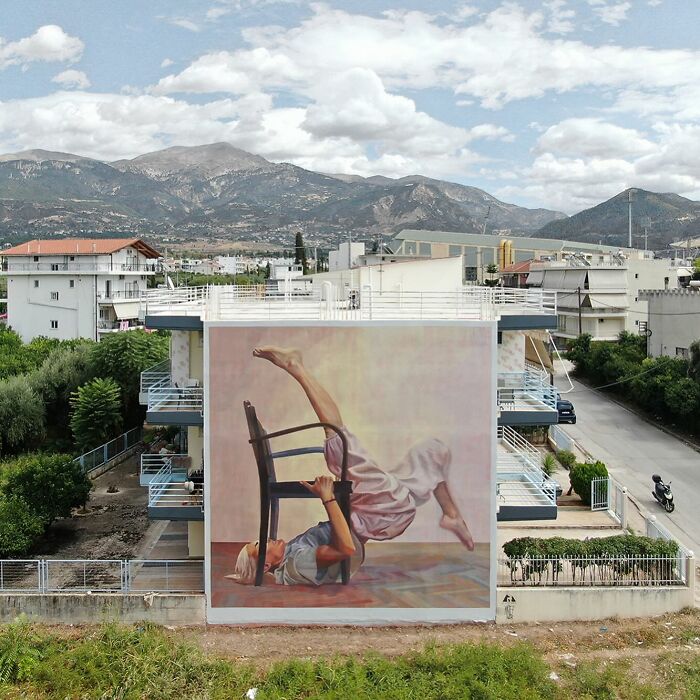 Colorful mural by Artez on a building wall depicting a person in a dynamic pose, enhancing the urban landscape.
