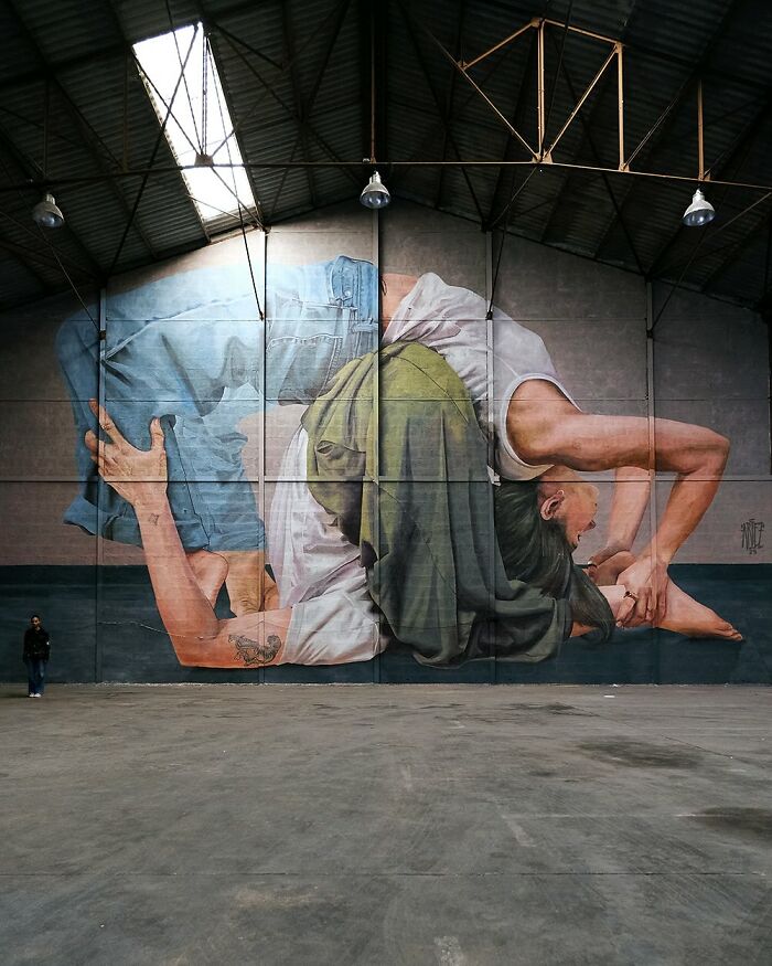 Large colorful mural by Artez showing intertwined figures painted inside an industrial building, enhancing urban art and city life.