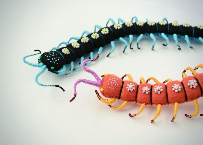 Two colorful felted artworks of centipedes with floral decorations, showcasing cute and weird felted art styles.