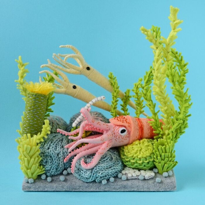 Felted artwork of a pink squid among green seaweed and blue coral, showcasing cute and weird felted creations.