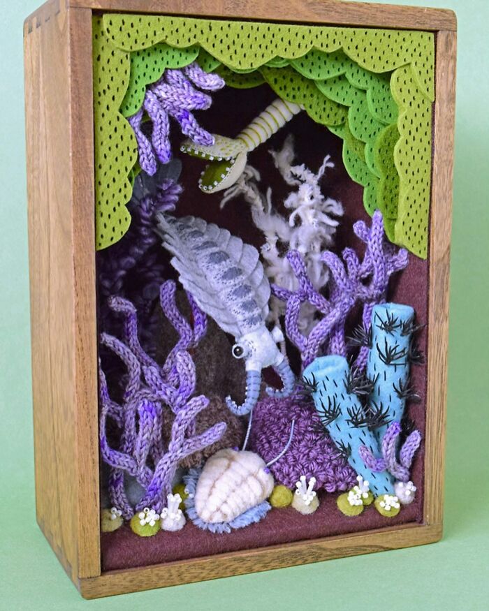 Felted underwater scene artwork featuring purple coral, a shrimp, and blue sea plants in a wooden shadow box.