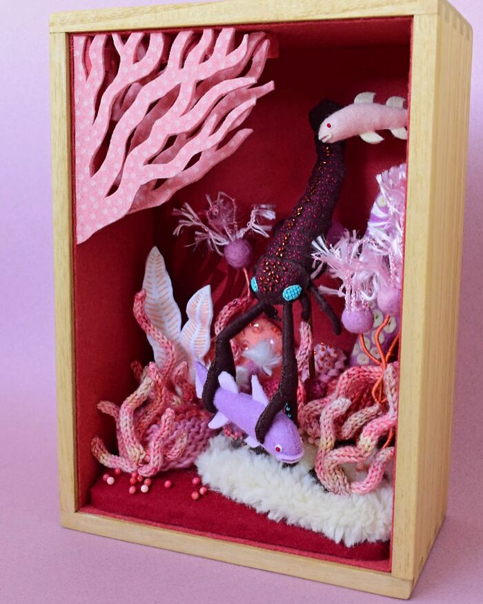 Felted artwork of an underwater scene with colorful coral, fish, and a large black sea creature in a wooden shadow box.