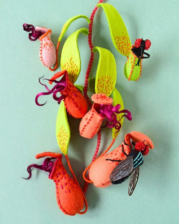 Felted artworks of colorful pitcher plants and insects made with detailed wool and embroidery on a green background.