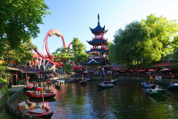 Colorful amusement park in Denmark with boats on the water and traditional architecture showcasing Danish culture.