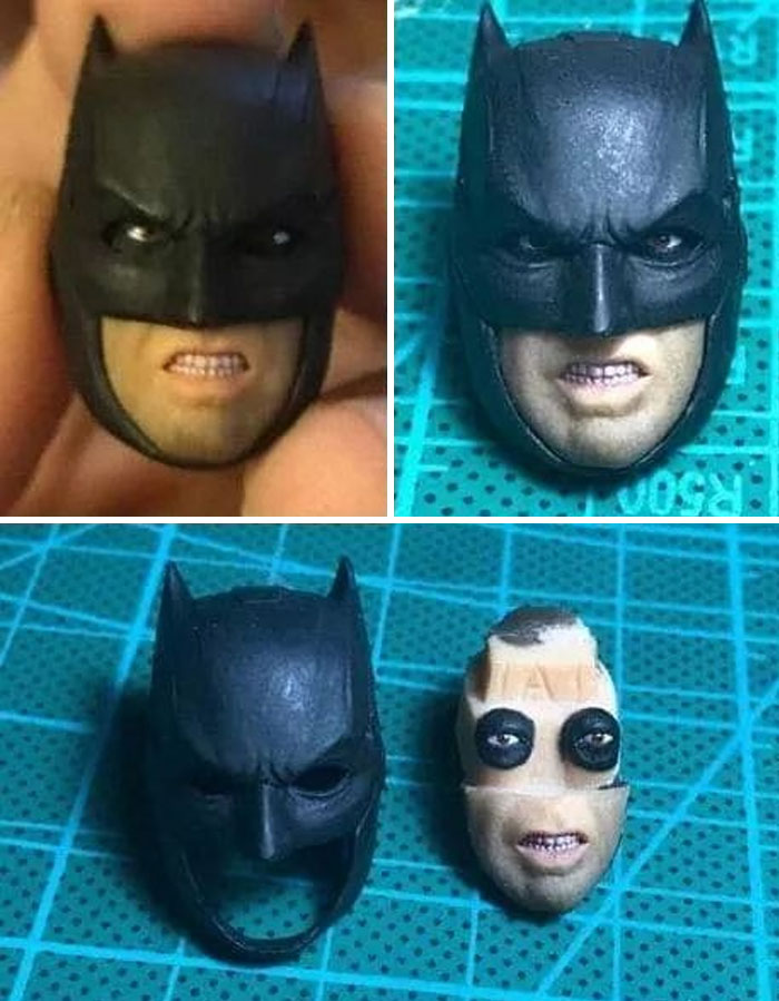 Close-up of a weird Batman figure head with a cursed expression, showing parts separated on a green cutting mat.