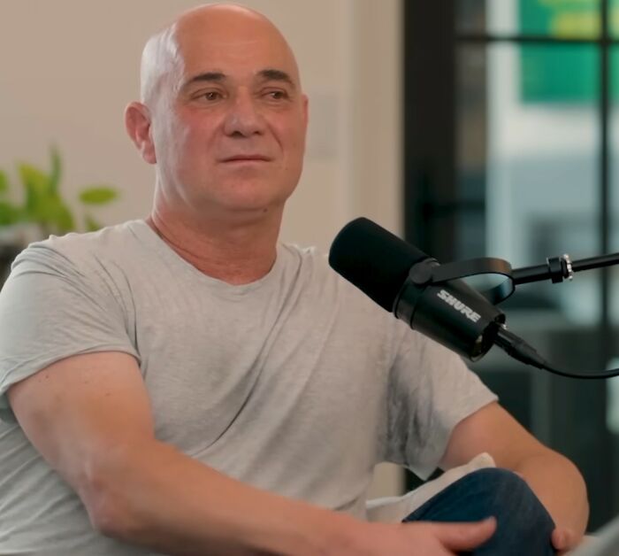 Bald man speaking into a microphone during a podcast, reflecting on moments meeting an idol that changed his life.