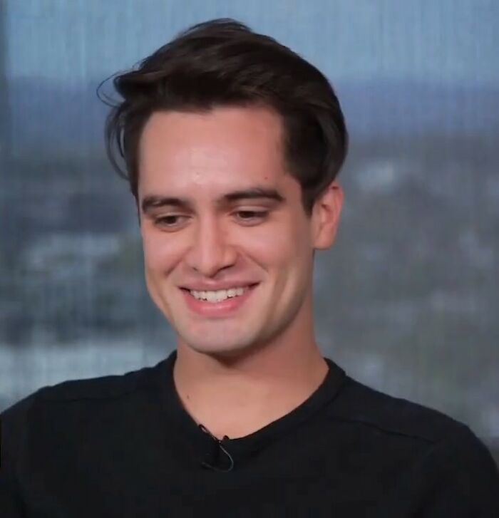 Young man smiling warmly during an interview, sharing stories about meeting an idol and unforgettable experiences.