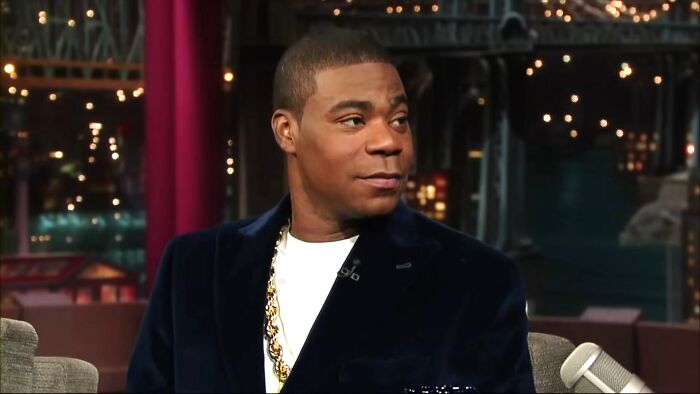 Comedian and actor in a dark blazer sharing a moment during a talk show about meeting an idol experiences.