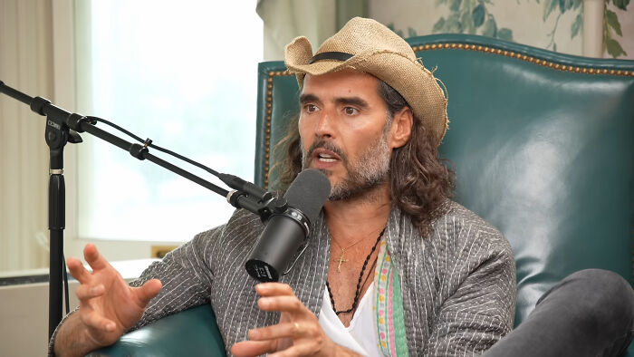 Man in a cowboy hat speaking into a microphone during a podcast interview about meeting an idol experiences.
