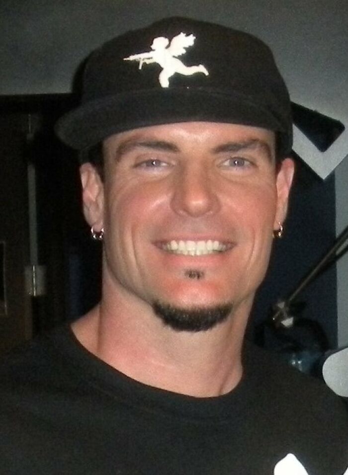 Man wearing a black cap with cupid design smiling, representing people who ran into celebrities and had worst experiences.