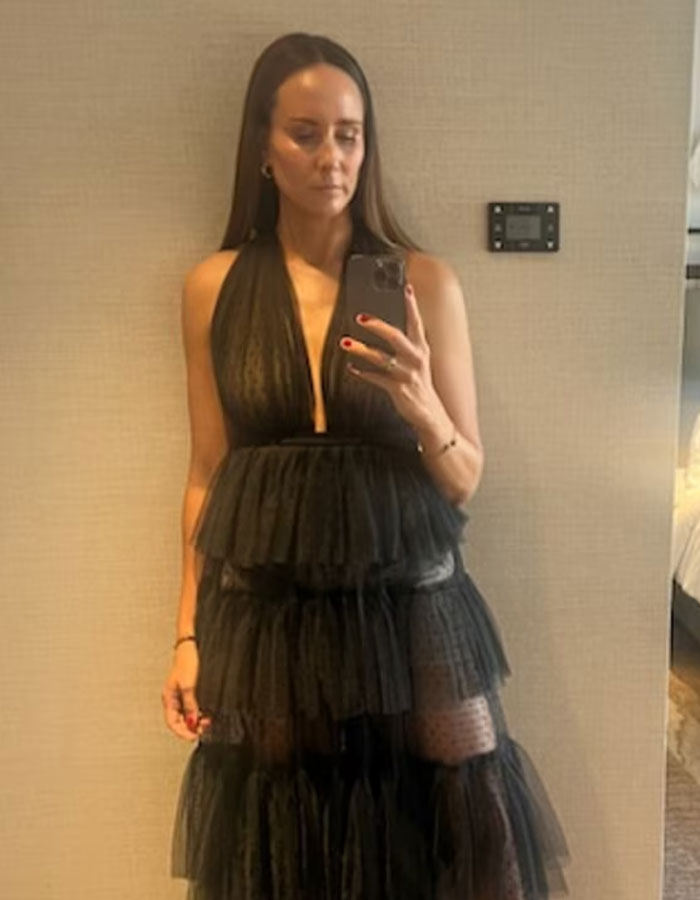 Woman in layered black dress taking a mirror selfie highlighting issues of woman told to cover up at pub and double standards.