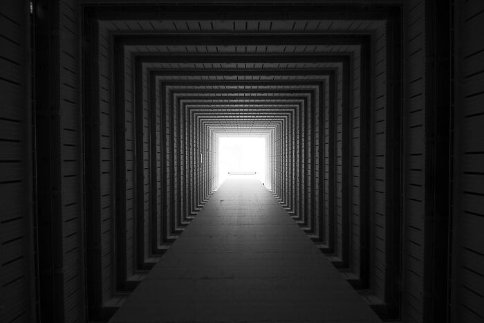 Looking up through a tall, symmetrical building corridor emphasizing depth and perspective in black and white.