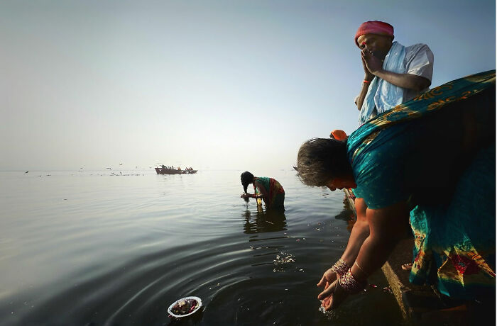 People performing daily rituals by the water, capturing candid moments of everyday life in Istanbul at dawn.