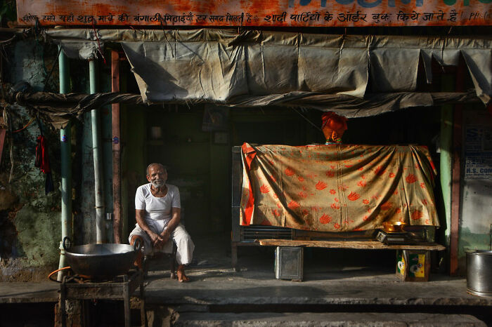 Elderly man sitting outside a rustic building in Istanbul, captured in a candid moment of everyday life.