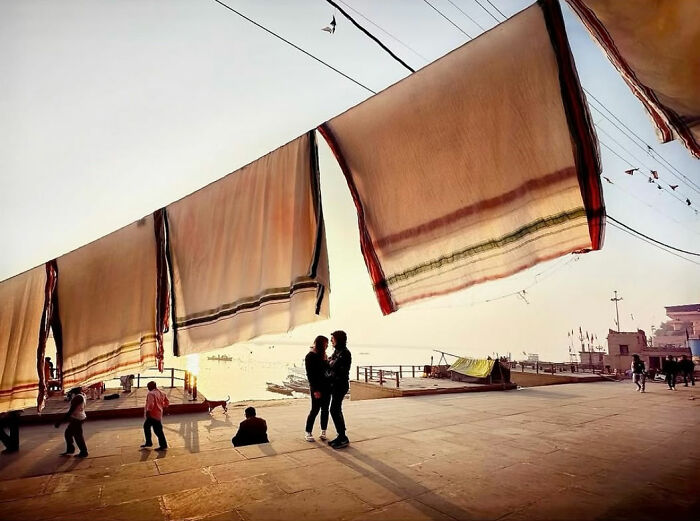 Large fabric pieces hanging on lines with people walking and socializing in a candid everyday life moment in Istanbul.