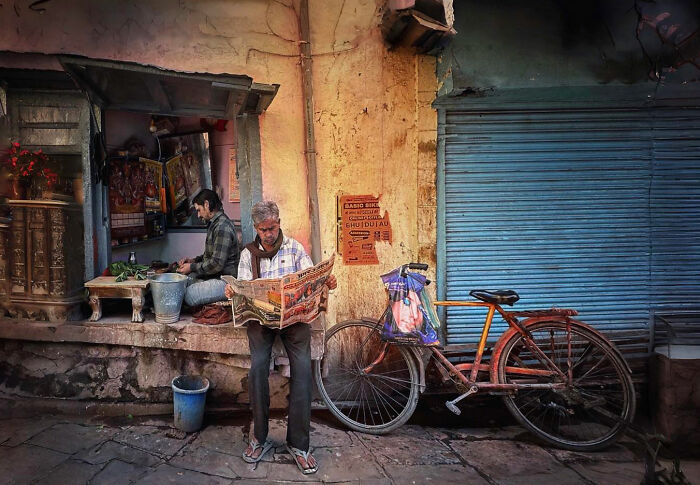 Man reading a newspaper outside a shop with a bicycle parked nearby, capturing candid moments of everyday life in Istanbul.