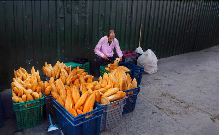 Man arranging fresh bread in baskets on the street, capturing candid moments of everyday life in Istanbul.