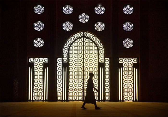 Silhouette of a person walking inside a grand, ornately patterned window, capturing everyday life in Istanbul.