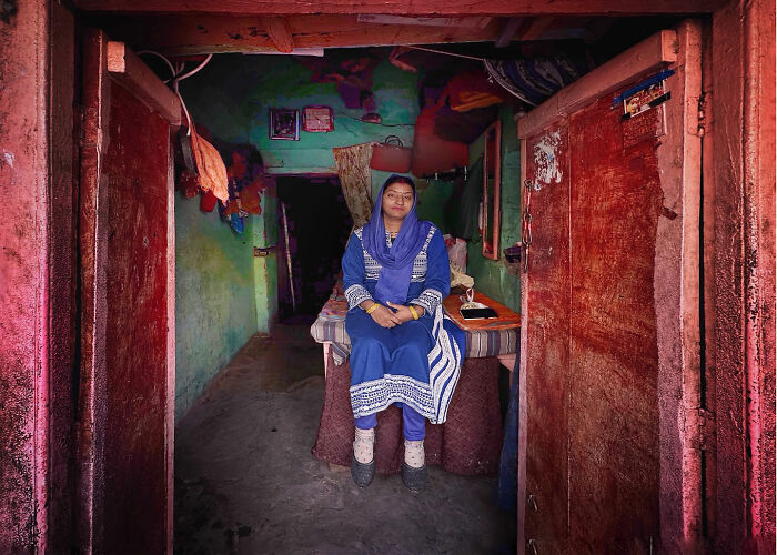 Woman in traditional attire sitting inside a weathered room, capturing candid moments of everyday life in Istanbul.