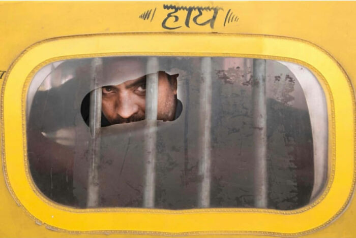 Man looking through bars of a yellow vehicle window in candid moments of everyday life in Istanbul by Yücel Çetin