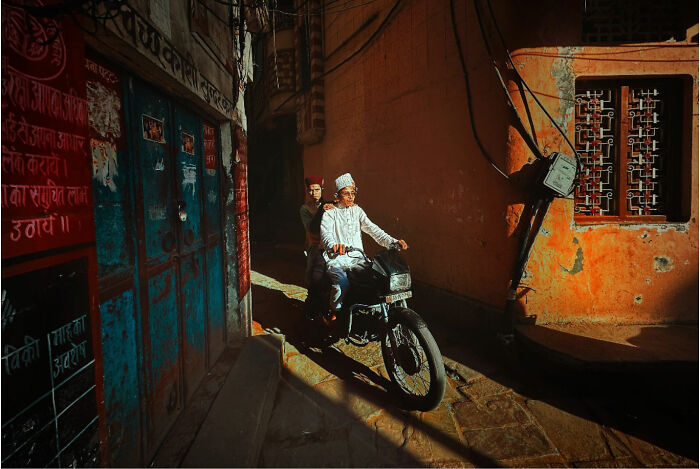 Two men riding a motorcycle through a narrow sunlit street capturing candid moments of everyday life in Istanbul.