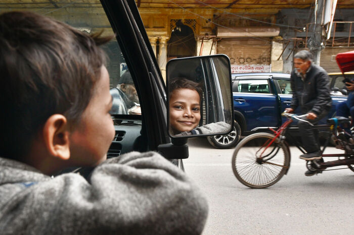 Young boy smiling at his reflection in a car mirror, capturing candid moments of everyday life in Istanbul.