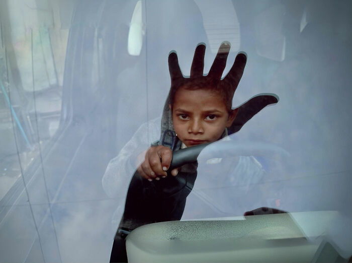 Young boy with hand pressed on glass inside a vehicle, capturing candid moments of everyday life in Istanbul.