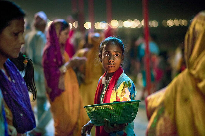 Young girl holding a green basket in a crowded night scene, capturing candid moments of everyday life in Istanbul.