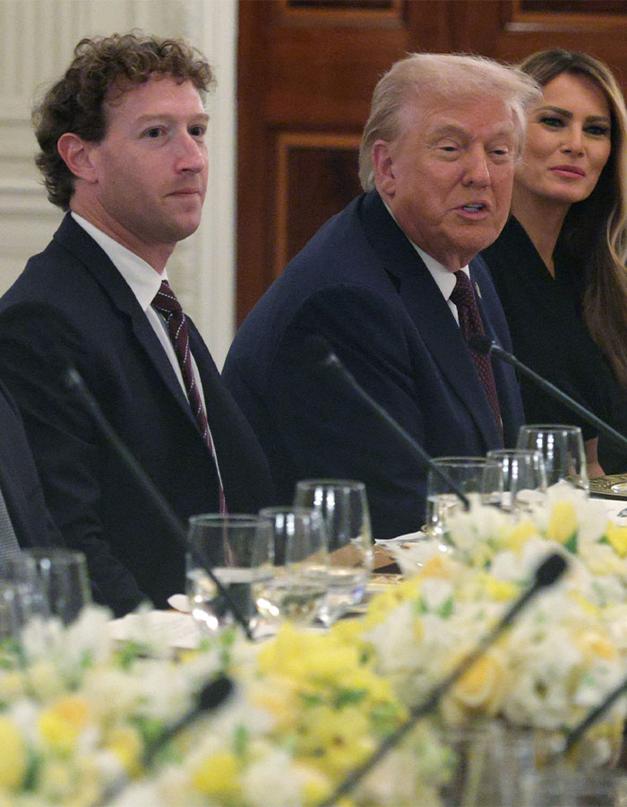 Mark Zuckerberg sitting beside Donald Trump and Melania Trump at a formal event with a floral centerpiece on the table.