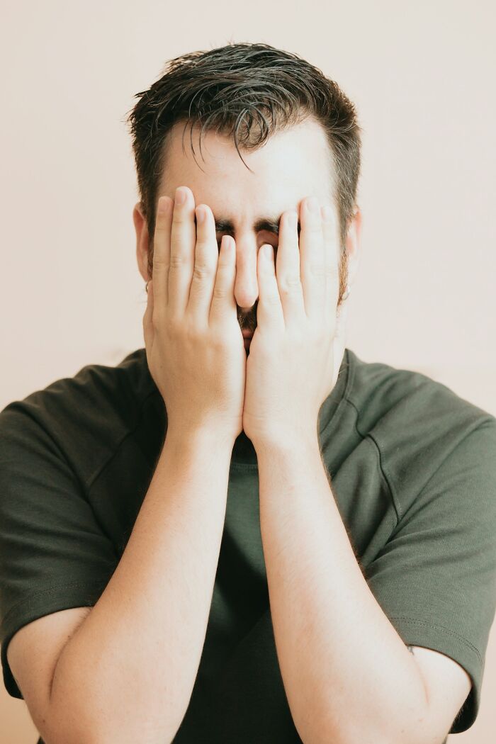 Man covering his face with hands in frustration, reflecting moments of people getting fired due to dumb mistakes.