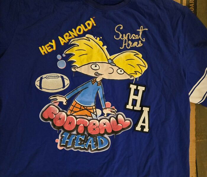 Blue Hey Arnold shirt with cartoon character and football graphics, illustrating absurd dealbreakers in relationships concept.