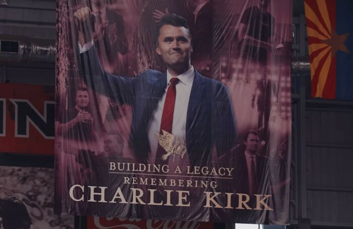 Banner displaying Charlie Kirk raising his fist, symbolizing legacy and related to Erika Kirk's gesture during husband's funeral viral moment.