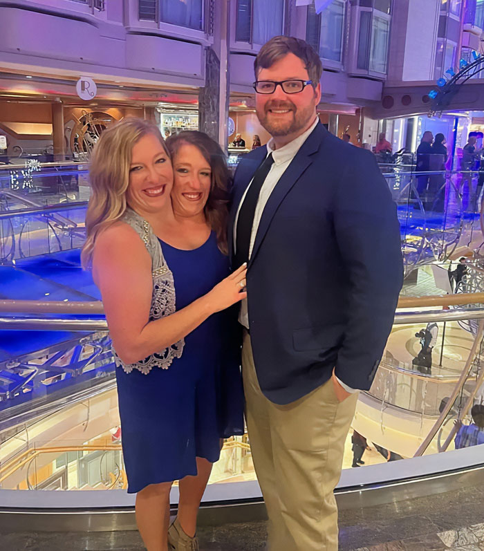 After conjoined twins Abby and Brittany smiling with a man in a formal setting, expert discusses who would be the mom.