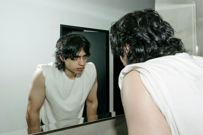 Young man looking frustrated in mirror, reflecting on getting fired quickly for not showing up to work.