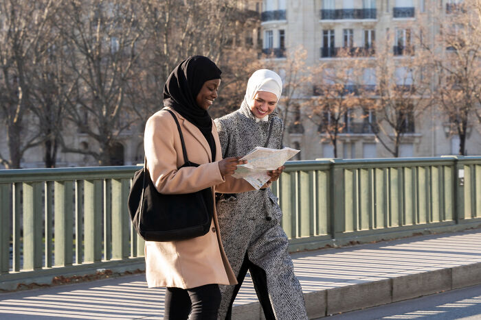 Two women wearing hijabs walk outdoors together, reflecting on life after the glory days of high school stars.