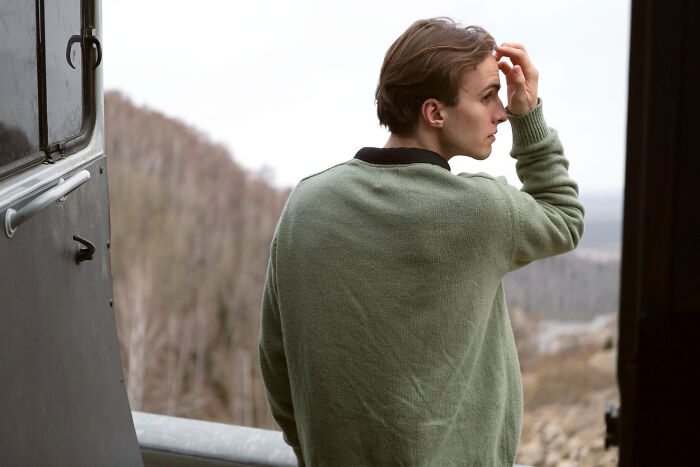 Young man reflecting outside a building, symbolizing people whose glory days were in high school and life afterward.