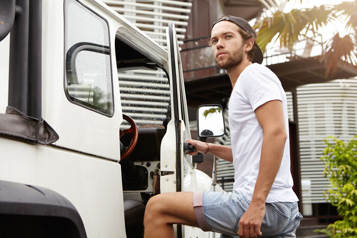 Young man, a former high school star, looking thoughtful as he enters a vintage white vehicle, reflecting life after glory days.